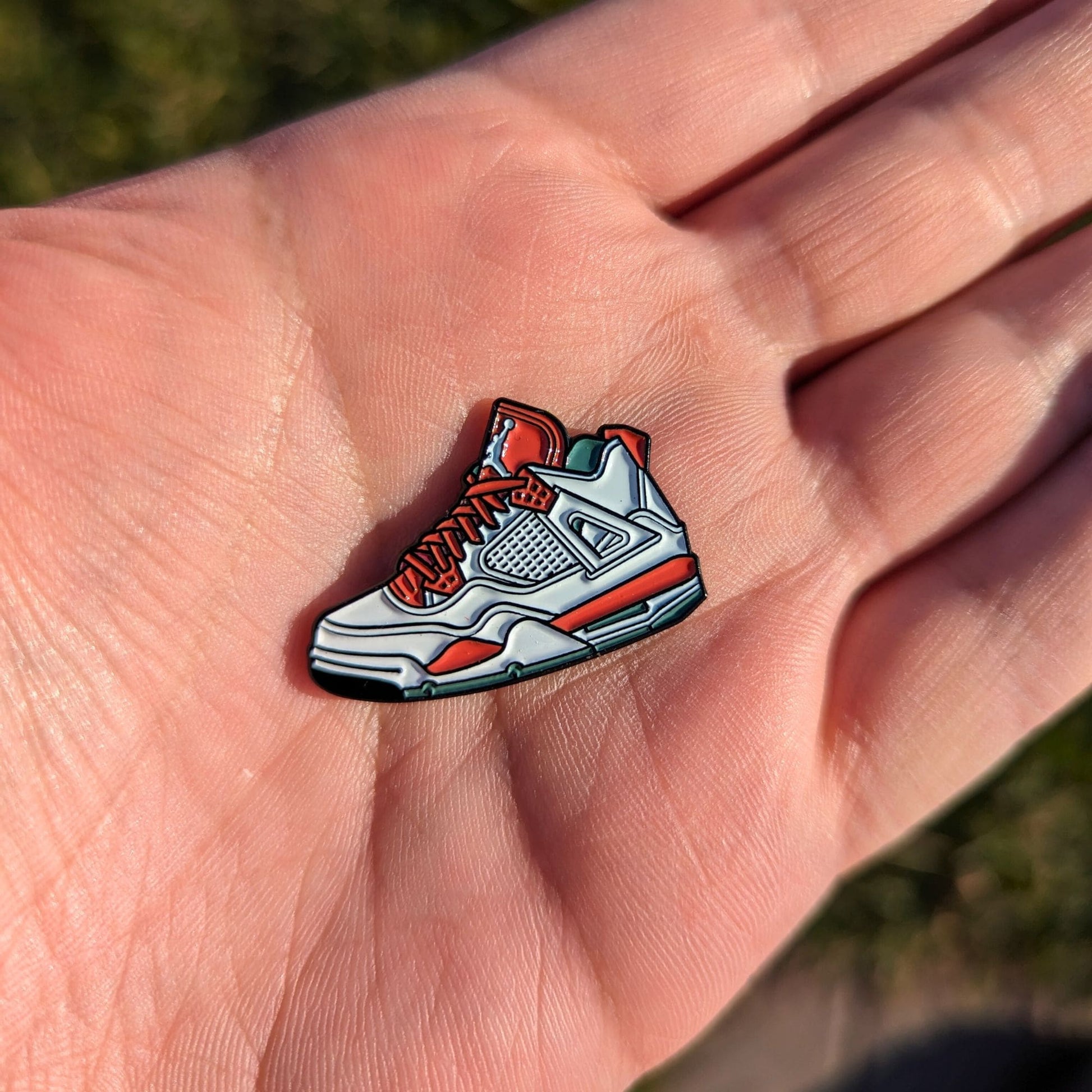 red and white sneaker golf ball marker in hand