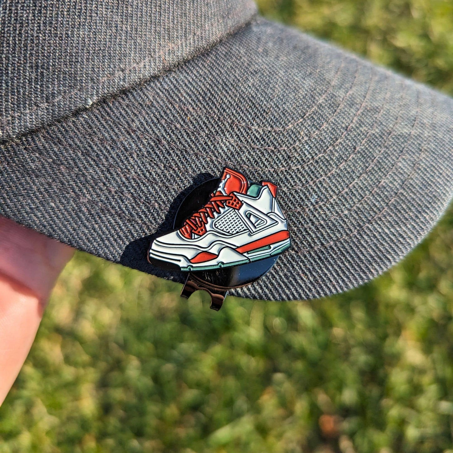 red and white sneaker golf ball marker clipped on hat